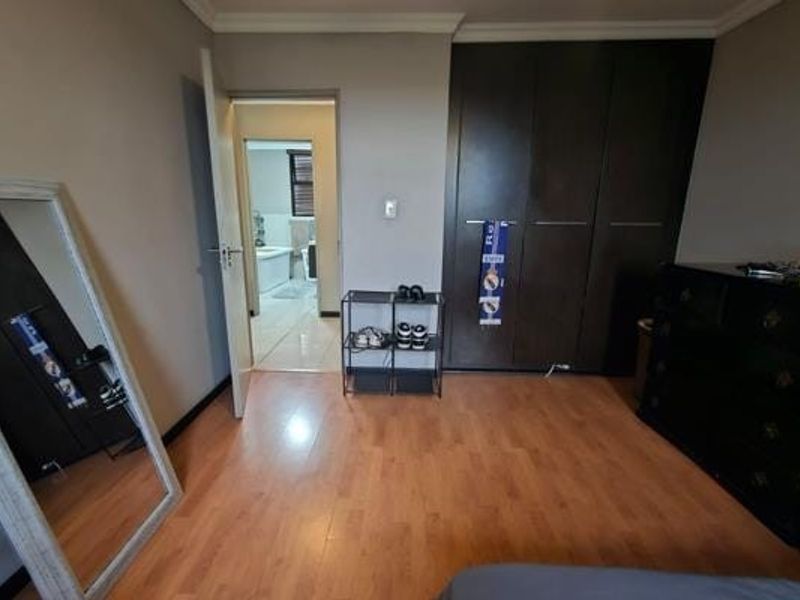 A bedroom featuring laminate flooring and dark built-in cupboards, with direct access to an en-suite bathroom.