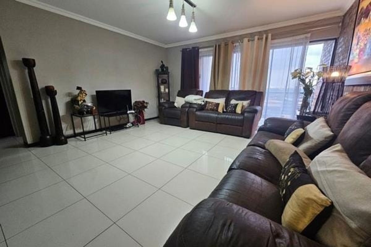 Spacious living room featuring polished tile flooring, modern ceiling lighting, and large sliding glass doors providing access to the balcony.