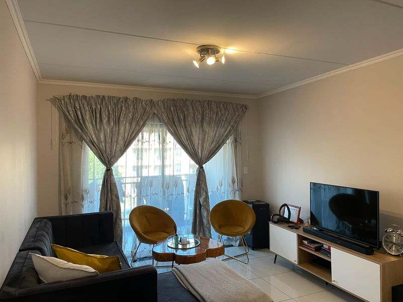 A well-lit living room featuring tiled flooring and a sliding glass door that provides access to an outdoor balcony area.