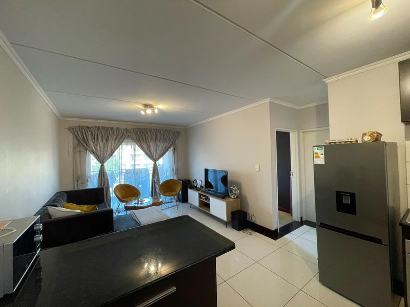 Open plan living area featuring tiled flooring, a kitchen counter, and a sliding door leading to a balcony.