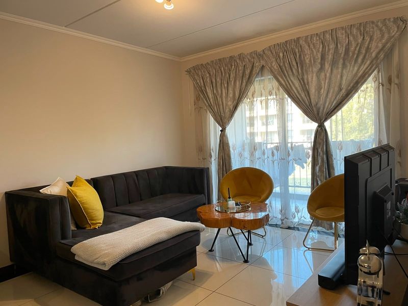A well-maintained living room featuring polished tile flooring, ceiling cornicing, and a large sliding glass door providing access to the balcony.