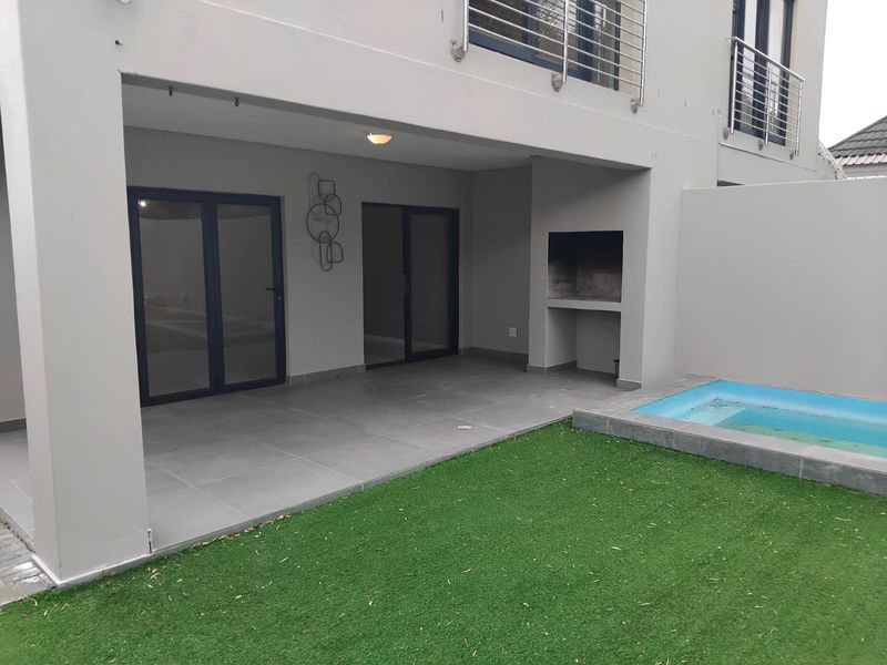 Covered patio area featuring a built-in braai, tiled flooring, and direct access to a small plunge pool and garden space.