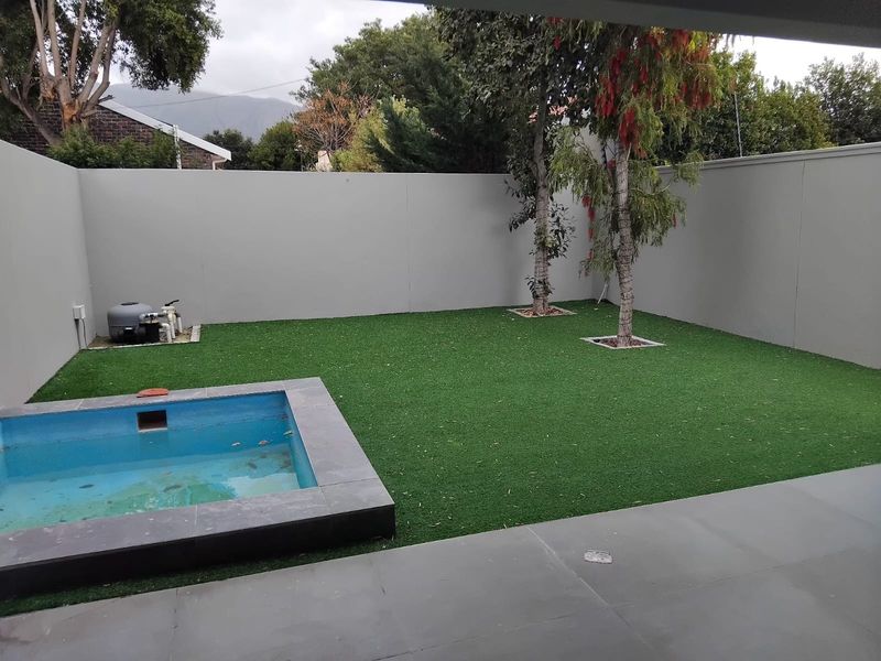 A private rear courtyard featuring a small plunge pool, artificial lawn, and high boundary walls for privacy.