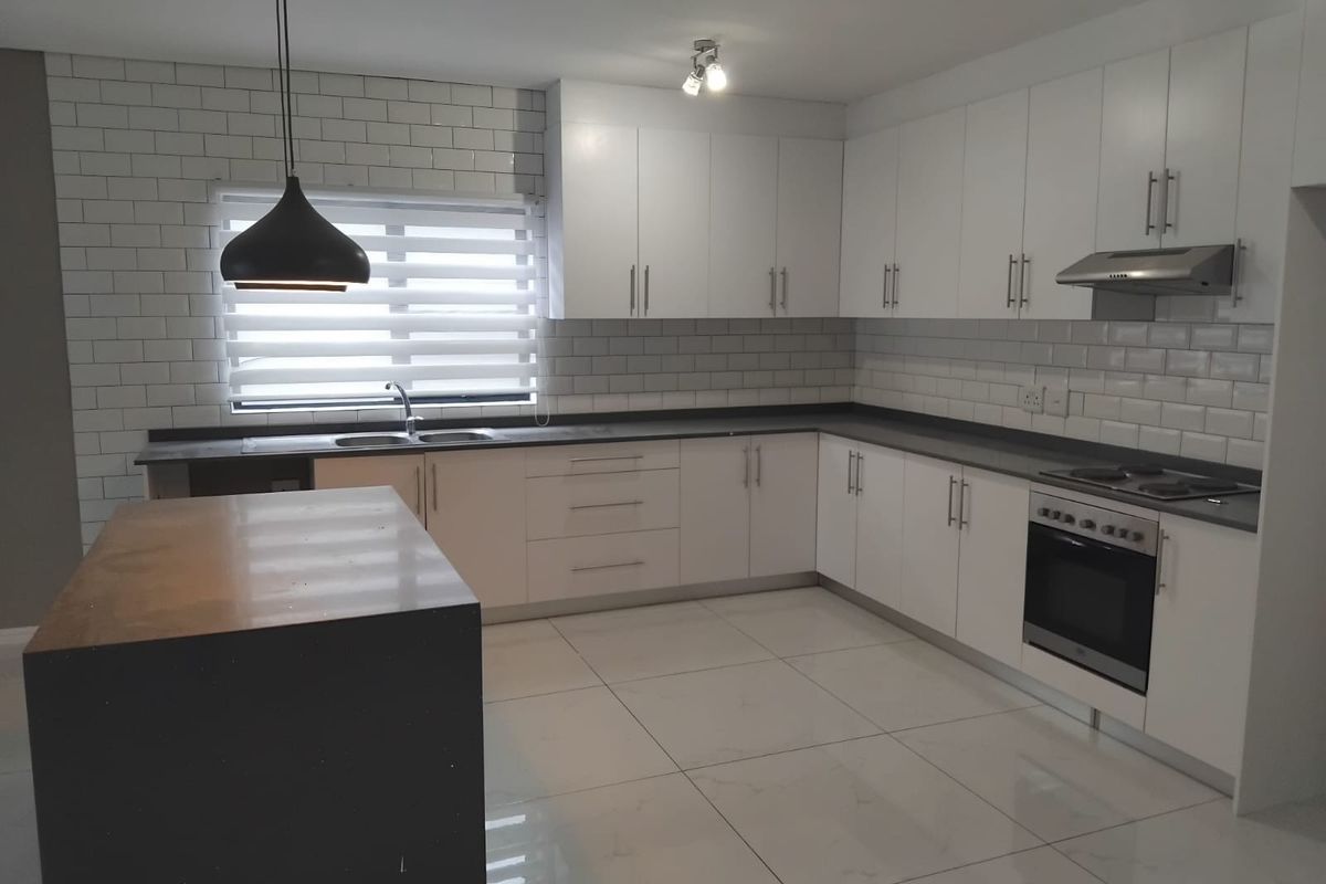 Modern kitchen featuring white cabinetry, quartz countertops, subway tile backsplash, built-in oven, hob, extractor fan, and large porcelain floor tiles.