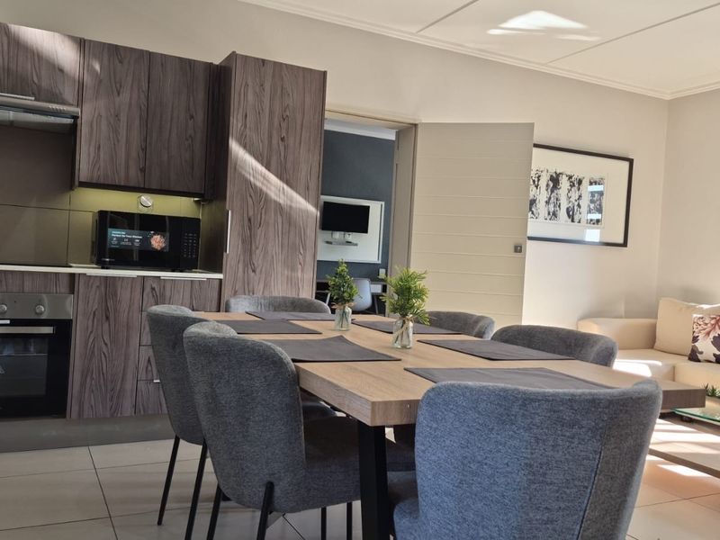 Modern open-plan living area featuring a contemporary kitchen with wood-grain cabinetry, integrated appliances, and seamless flow to the lounge and dining space.