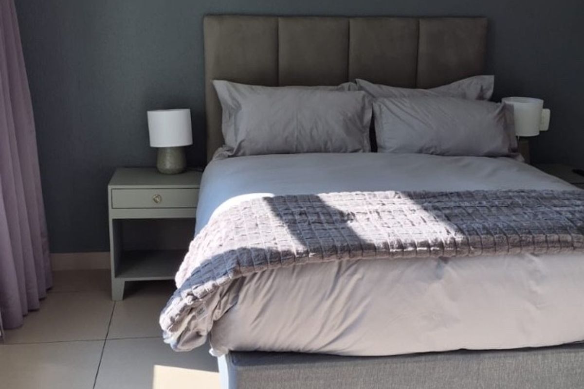 A well-maintained bedroom featuring neutral tiled flooring and modern recessed downlighting.