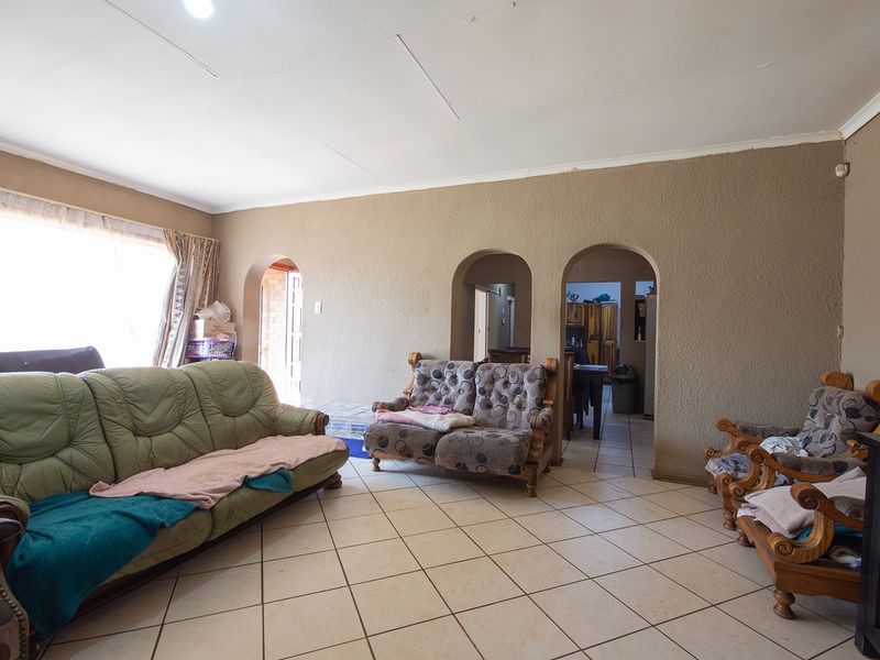 Spacious living area featuring tiled flooring and distinctive arched doorways leading to adjacent rooms, offering a functional layout with potential for modernization.