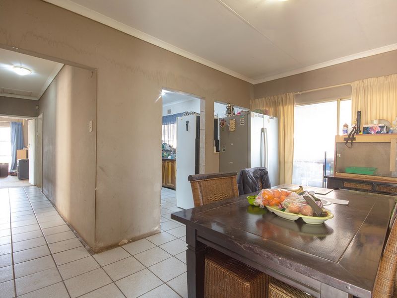 Dining area featuring tiled flooring and access to an outdoor space, with visible wear to wall finishes requiring maintenance or renovation.