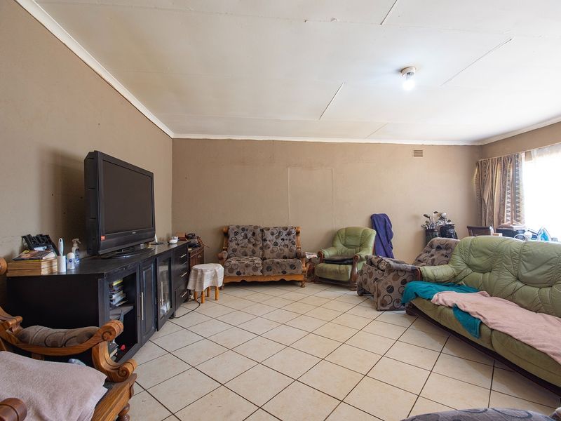 A living room featuring tiled flooring and cove cornicing, currently requiring cosmetic updates to the ceiling and wall finishes.