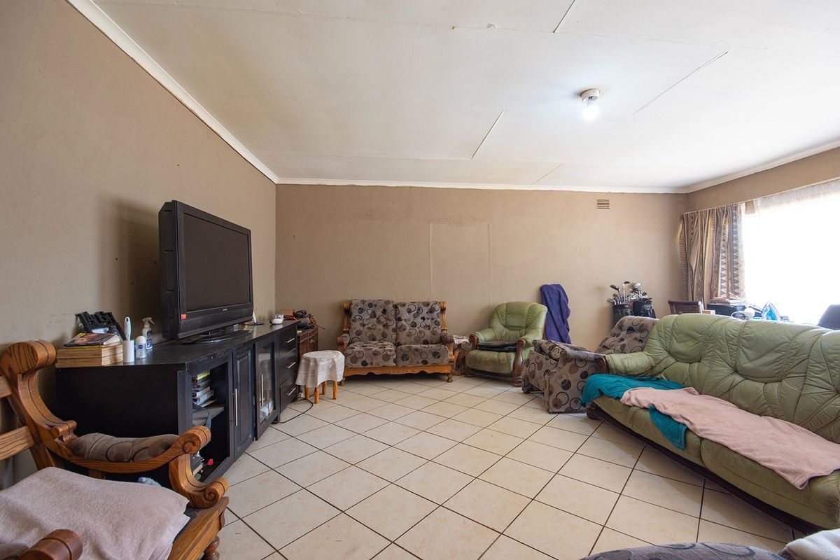 A living room featuring tiled flooring and cove cornicing, currently requiring cosmetic updates to the ceiling and wall finishes.
