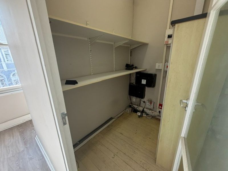 A small utility or server storage space featuring wall-mounted shelving, electrical infrastructure, and data cabling connections.