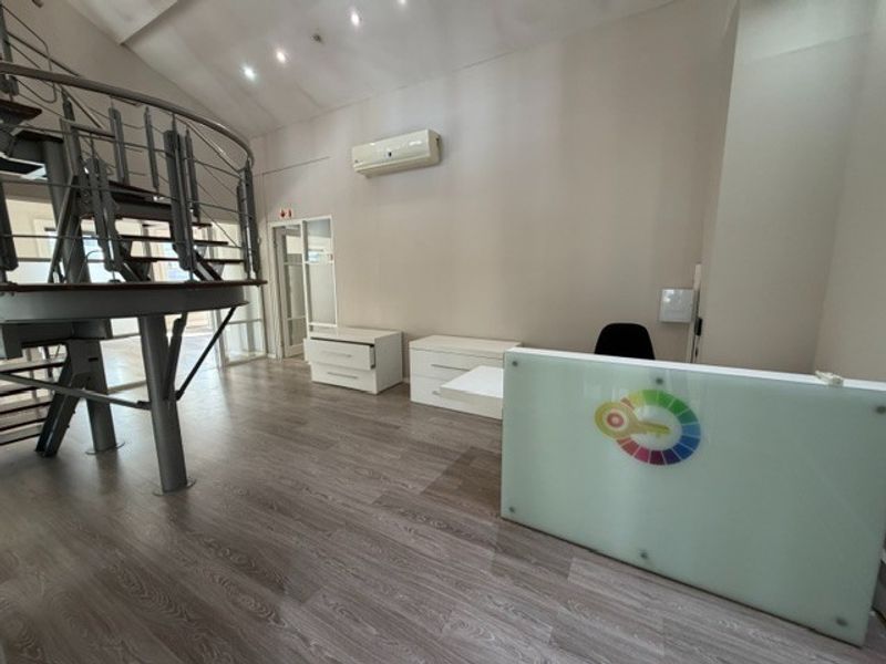 Modern office space featuring a prominent spiral staircase, laminate flooring, and a built-in reception desk with integrated air conditioning.