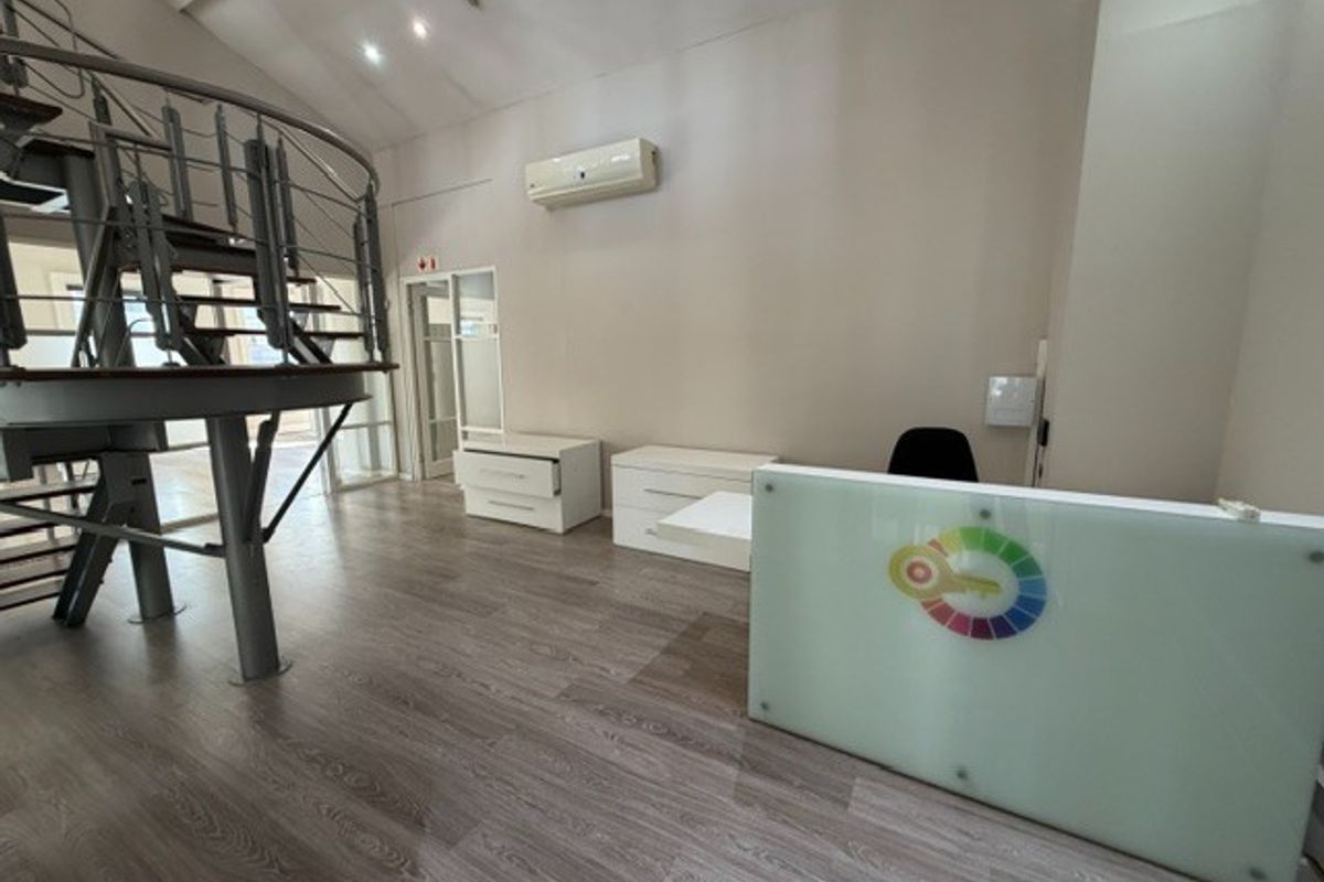 Modern office space featuring a prominent spiral staircase, laminate flooring, and a built-in reception desk with integrated air conditioning.