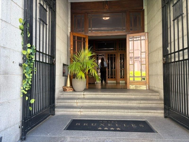 Grand entrance featuring stone steps, wrought iron gates, and classic timber-framed glass doors leading into the restaurant lobby.