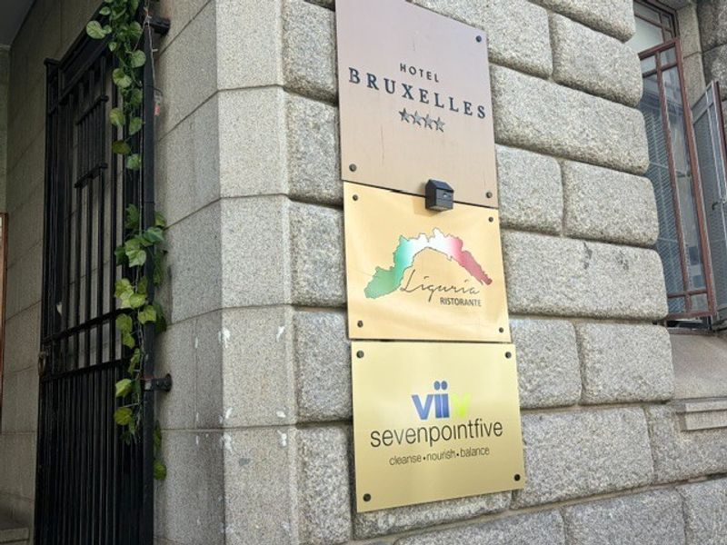 Exterior view of the building facade featuring stone masonry construction and multiple business signage plaques mounted on the wall.