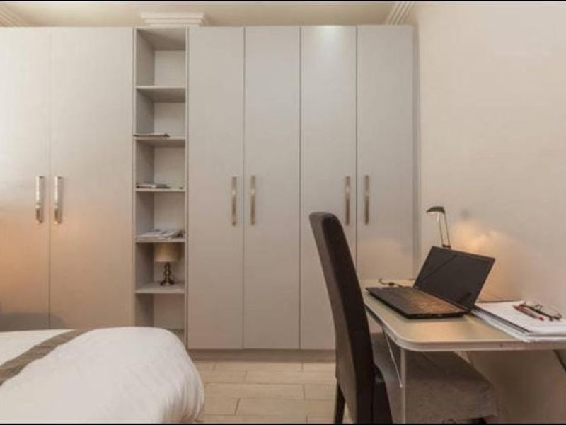A bedroom featuring extensive built-in cabinetry with integrated shelving and neutral tiled flooring.
