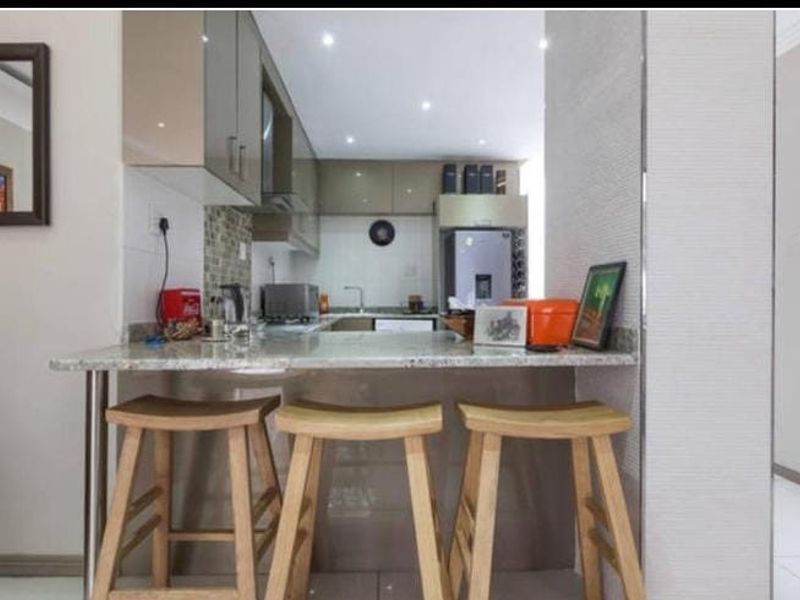 A compact, modern kitchen featuring a granite breakfast bar, sleek cabinetry, and a mosaic tile backsplash, providing a functional and stylish cooking space.