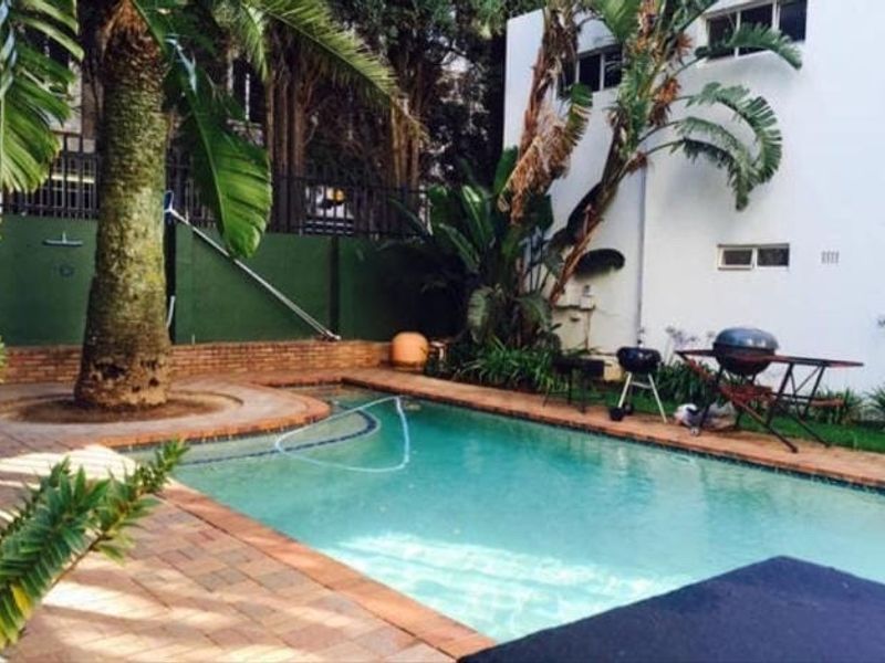 A private outdoor swimming pool area featuring brick paving, established landscaping, and a boundary wall, providing a functional space for outdoor recreation.