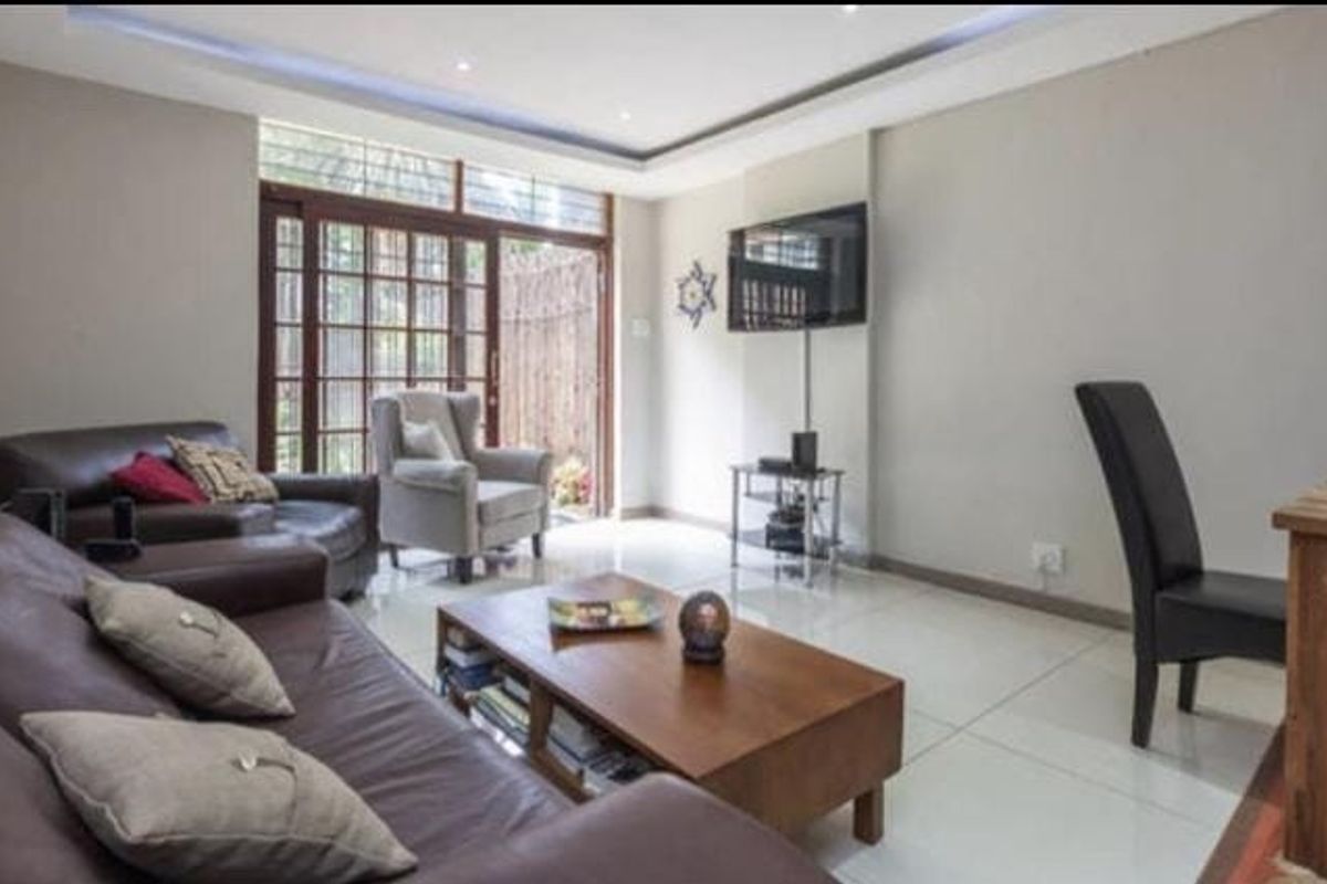 A bright living room featuring tiled flooring, recessed ceiling lighting, and a sliding glass door providing access to an outdoor area.