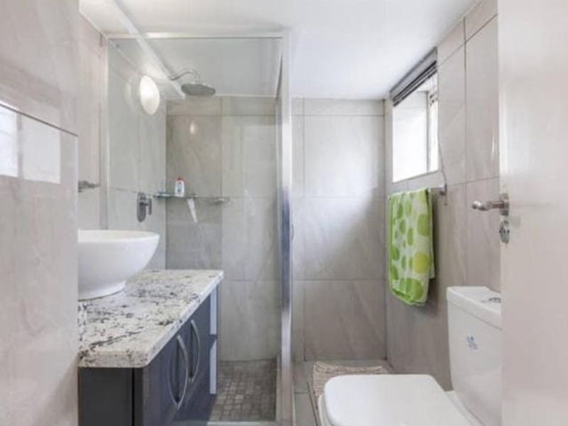 A compact bathroom featuring a modern vanity with granite countertop, vessel sink, and a glass-enclosed shower with tiled finishes.