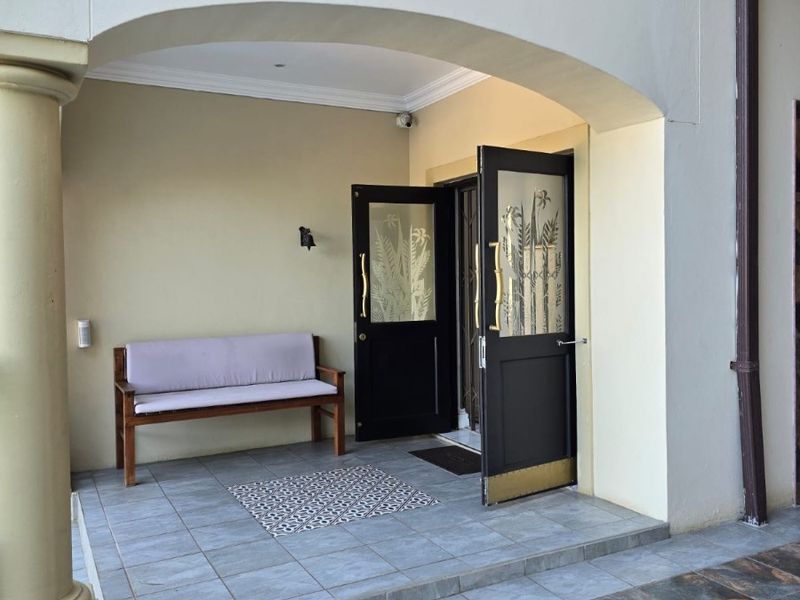A covered patio area featuring an arched entrance with double glass panel doors and tiled flooring.