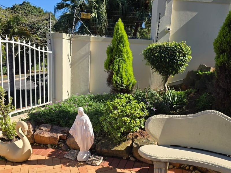 A paved outdoor patio area featuring a perimeter wall with electric fencing and a secure gated entrance.
