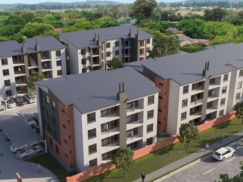 Aerial view of a modern multi-story apartment complex featuring brick and plaster facades, pitched roofs, and dedicated covered parking areas.