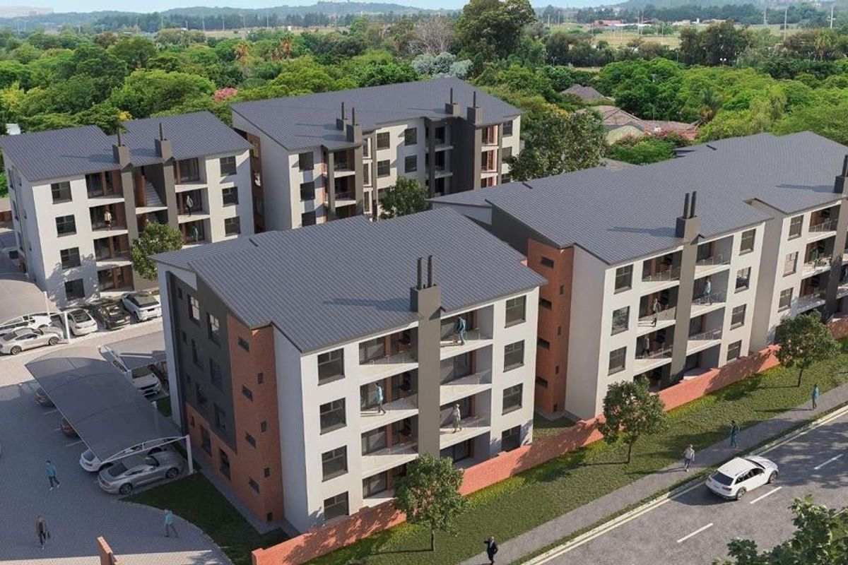 Aerial view of a modern multi-story apartment complex featuring brick and plaster facades, pitched roofs, and dedicated covered parking areas.