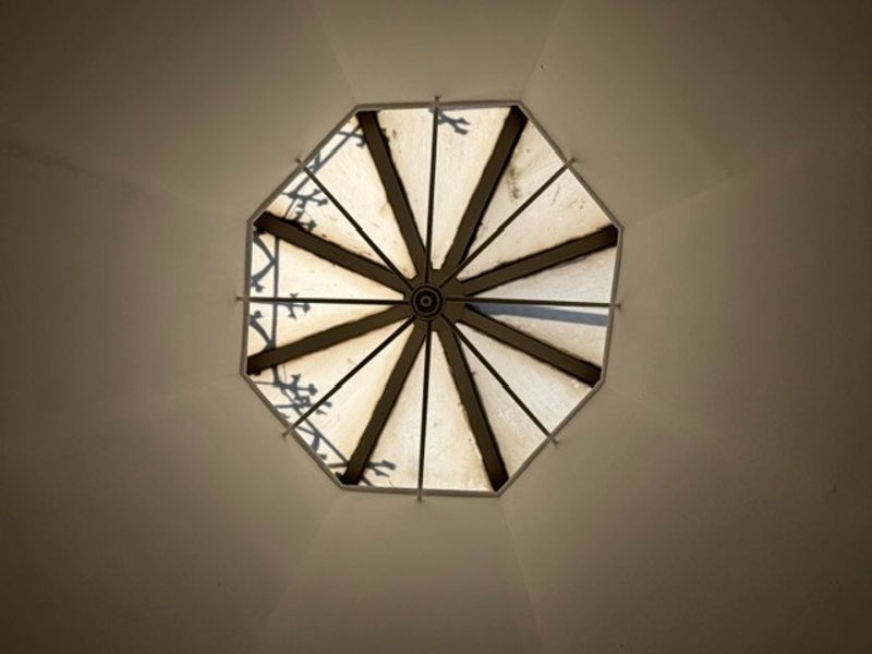 An upward view of an octagonal skylight feature set into the ceiling, showing signs of weathering and staining on the glazing panels.