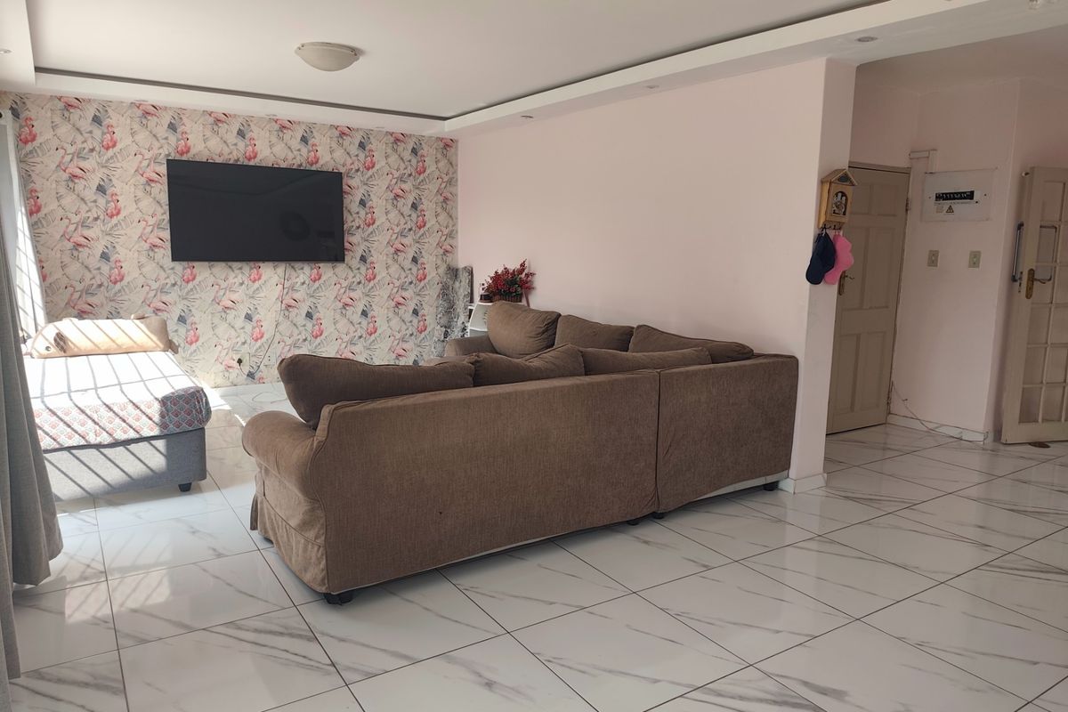 Spacious living area featuring modern white marble-look porcelain floor tiles, a decorative feature wall, and recessed ceiling lighting.