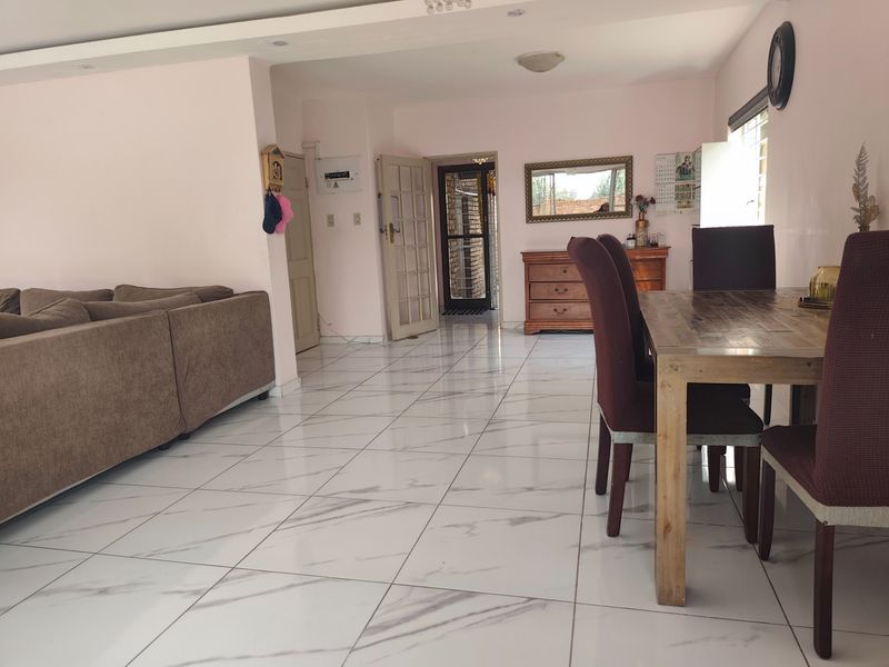 Spacious open-plan living and dining area featuring modern marble-look floor tiles and recessed ceiling lighting, creating a bright and functional living space.