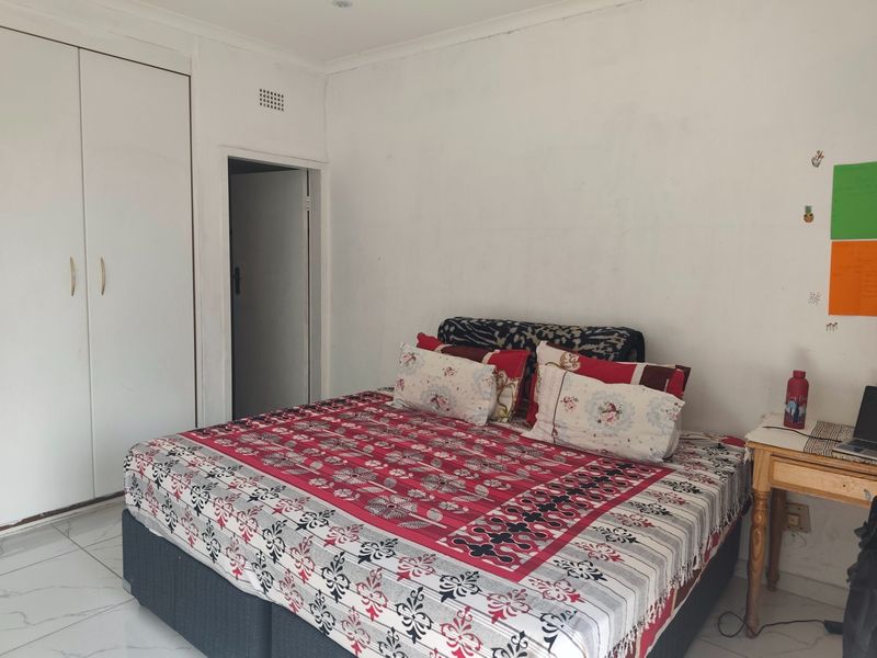 A bedroom featuring tiled flooring and a built-in wardrobe, providing a functional space with neutral wall finishes.