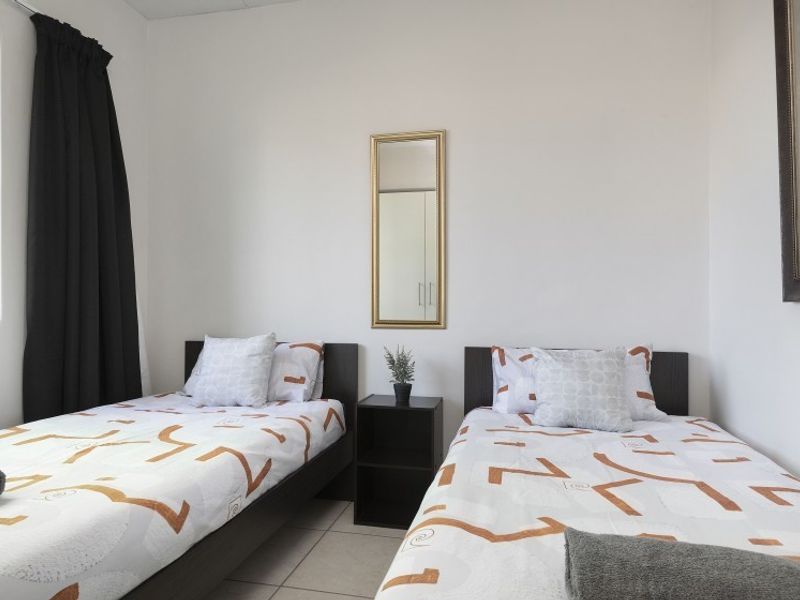 A clean and functional bedroom featuring tiled flooring and a built-in wardrobe, offering a neutral space ready for personalization.