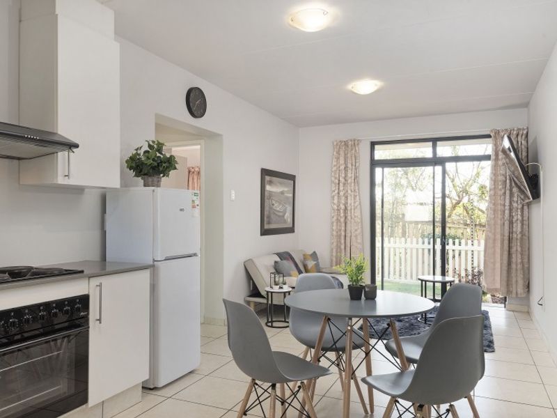 Open-plan living area featuring a modern kitchen with built-in appliances, tiled flooring, and sliding glass doors leading to an outdoor space.