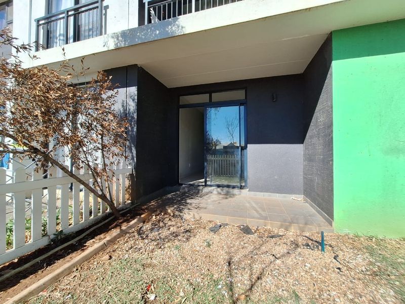 Ground floor patio area featuring tiled flooring and a sliding glass door entrance, adjacent to a small private garden space.