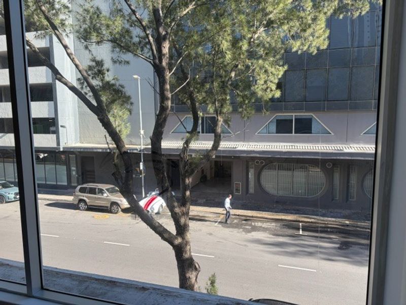 A view from an office window looking out onto a street and neighboring commercial building.