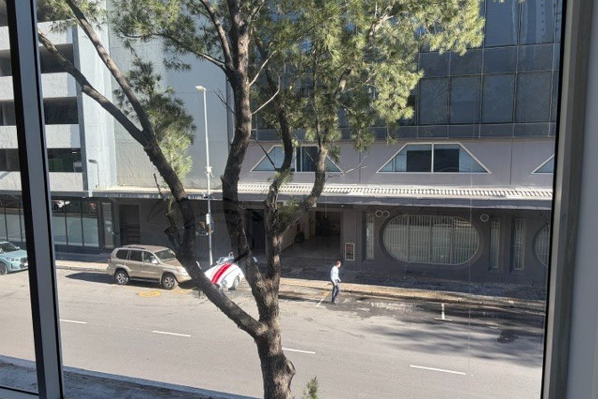A view from an office window looking out onto a street and neighboring commercial building.