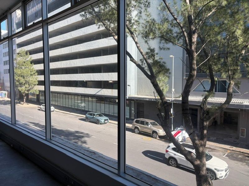 A view from an office window overlooking a city street and adjacent parking structure.