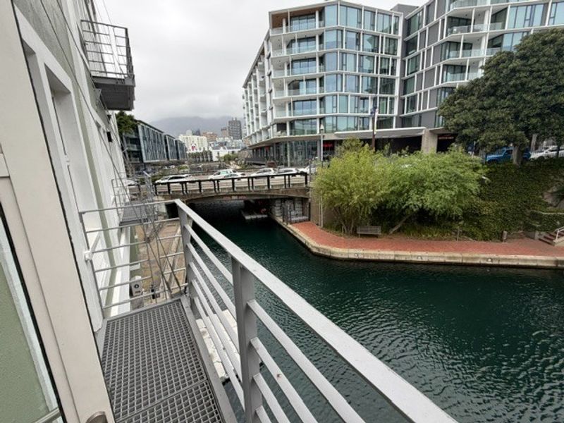 A metal balcony overlooking a canal and urban cityscape, providing an outdoor space with views of the surrounding architecture and waterway.