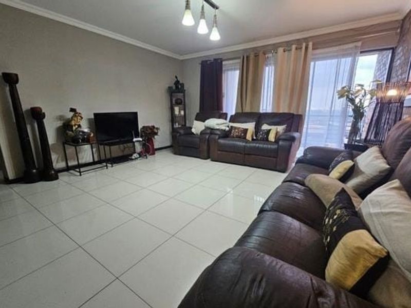 Spacious living room featuring polished tile flooring, modern ceiling lighting, and large sliding glass doors providing access to the balcony.