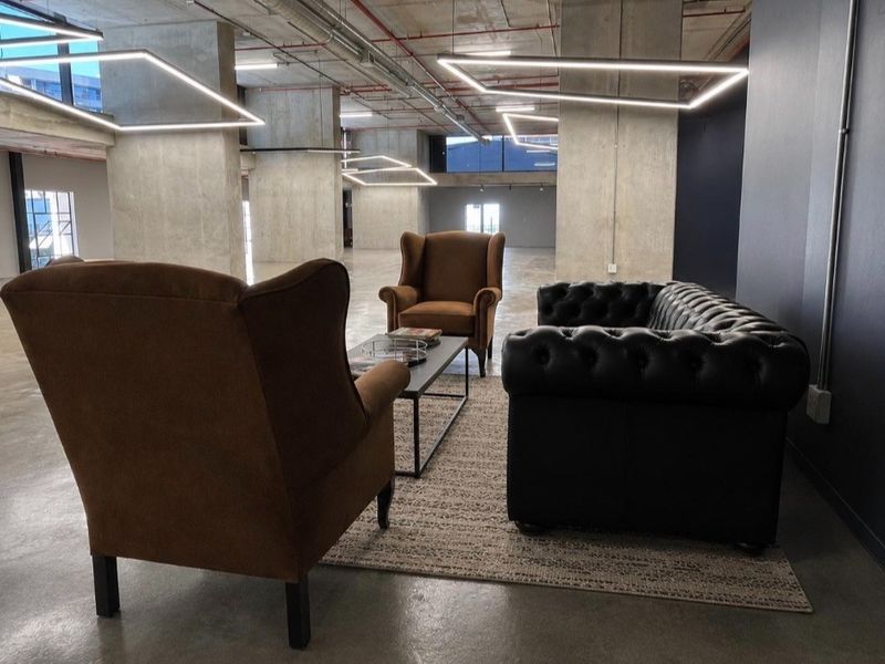 Spacious open-plan commercial area featuring industrial-style exposed concrete ceilings, columns, and polished concrete floors with modern suspended lighting.