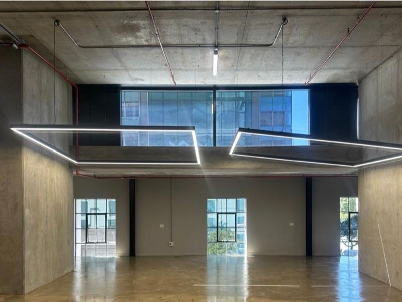 Spacious open-plan retail or commercial unit featuring high exposed concrete ceilings, polished concrete floors, and large windows providing ample natural light.