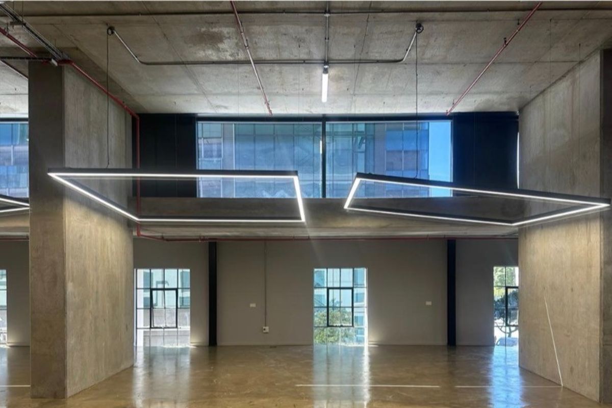 Spacious open-plan retail or commercial unit featuring high exposed concrete ceilings, polished concrete floors, and large windows providing ample natural light.
