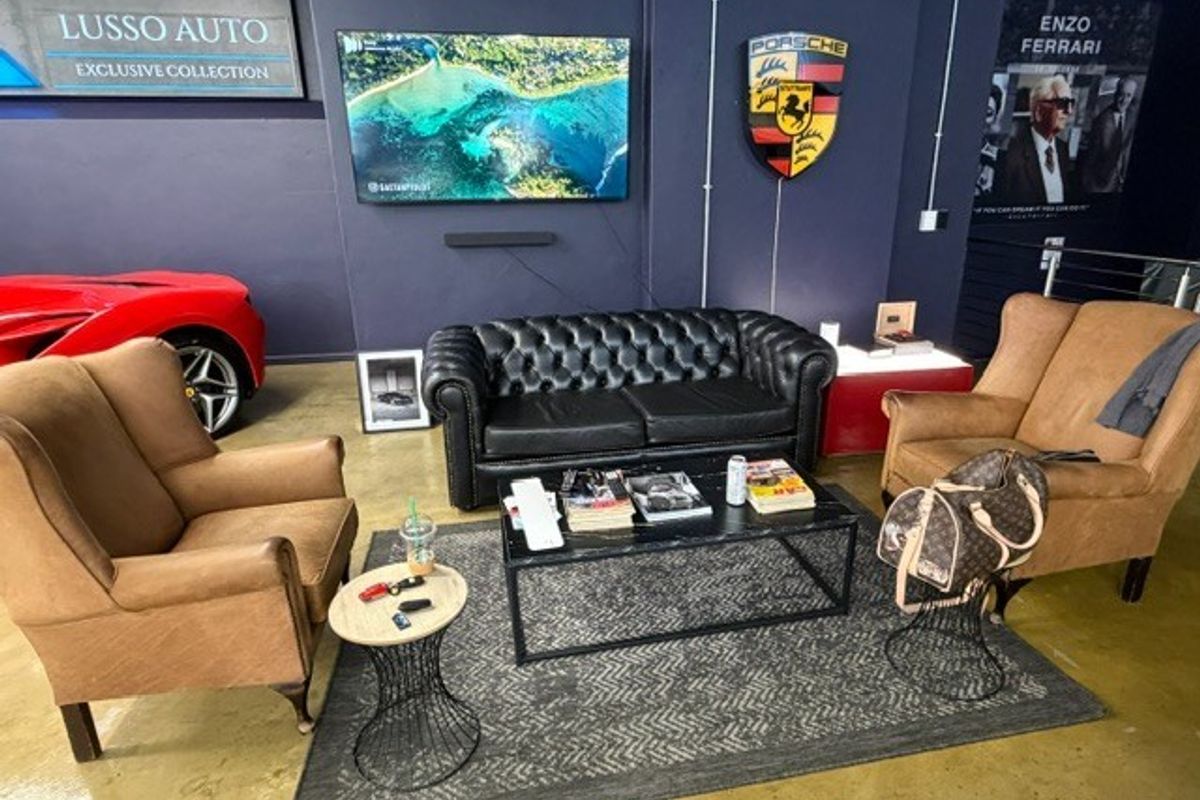 A lounge area within a commercial showroom space featuring polished concrete floors and dark painted walls.