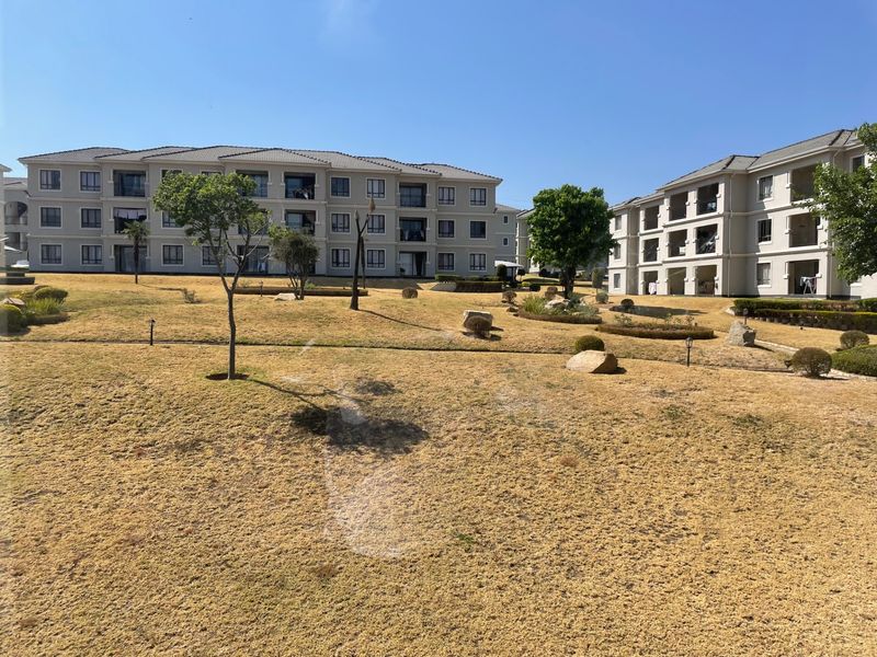 A view of the apartment complex exterior featuring multi-story residential blocks and a shared landscaped garden area.