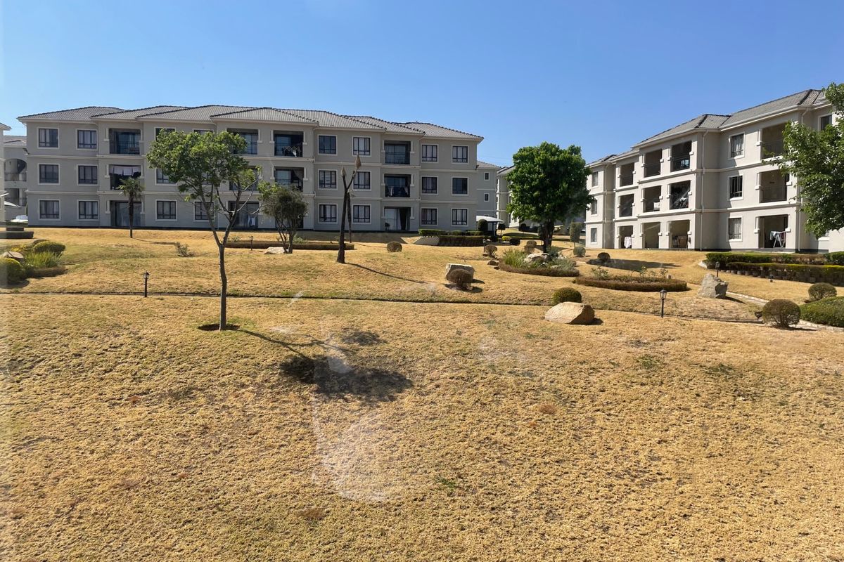 A view of the apartment complex exterior featuring multi-story residential blocks and a shared landscaped garden area.