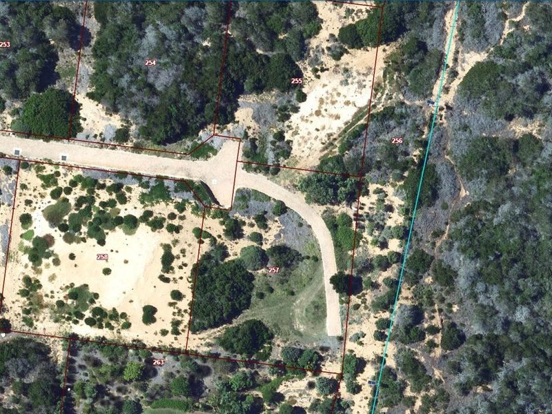 Aerial view of vacant residential land plots featuring natural vegetation, sandy terrain, and established access road infrastructure.