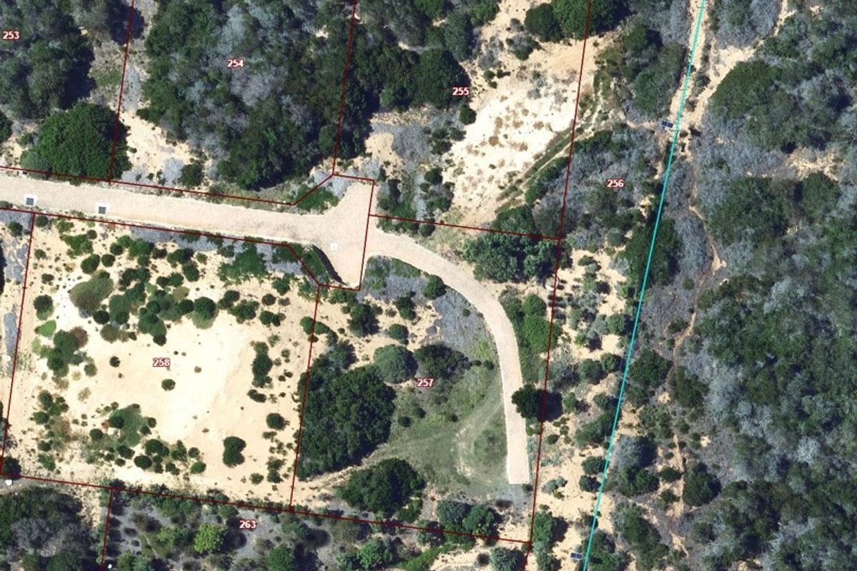 Aerial view of vacant residential land plots featuring natural vegetation, sandy terrain, and established access road infrastructure.