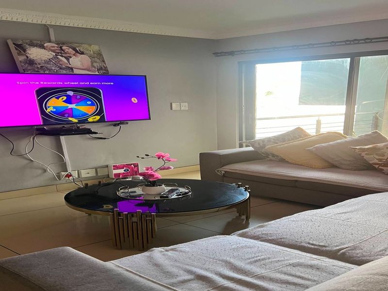A comfortable living room featuring tiled flooring, crown molding, and a large sliding glass door that provides access to the outdoor area.