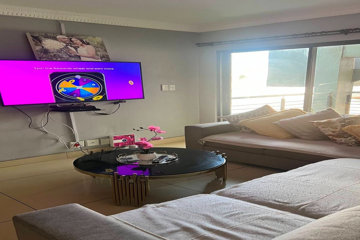A comfortable living room featuring tiled flooring, crown molding, and a large sliding glass door that provides access to the outdoor area.